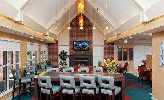 a modern , open - plan living area with a dining table and chairs , a fireplace , and a flat - screen tv at Residence Inn Lansing West