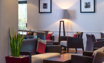 a modern lounge area with comfortable seating , a large window , and framed pictures on the wall at Holiday Inn Express Droitwich Spa