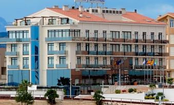 a large hotel building situated on the waterfront , surrounded by a body of water and a beach at Hotel Flamingo