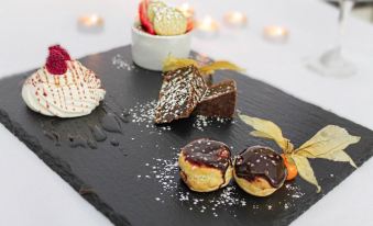 a black slate plate with various desserts and a small white bowl containing strawberries and chocolate drizzle at Best Western Preston Garstang Country Hotel and Golf Club
