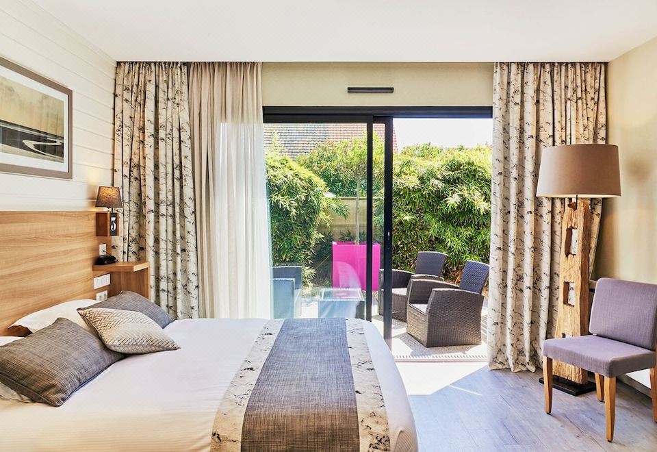 a bedroom with a bed and curtains , featuring a sliding glass door leading to a patio at La Cremaillere