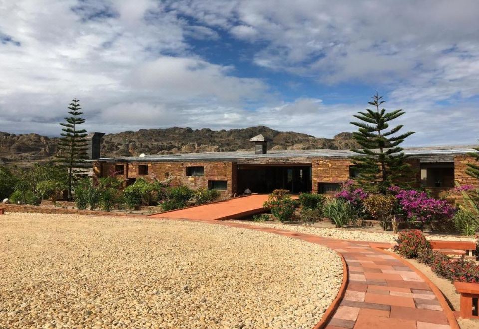 a brick house surrounded by a gravel walkway , with a garden in front of it at Isalo Rock Lodge