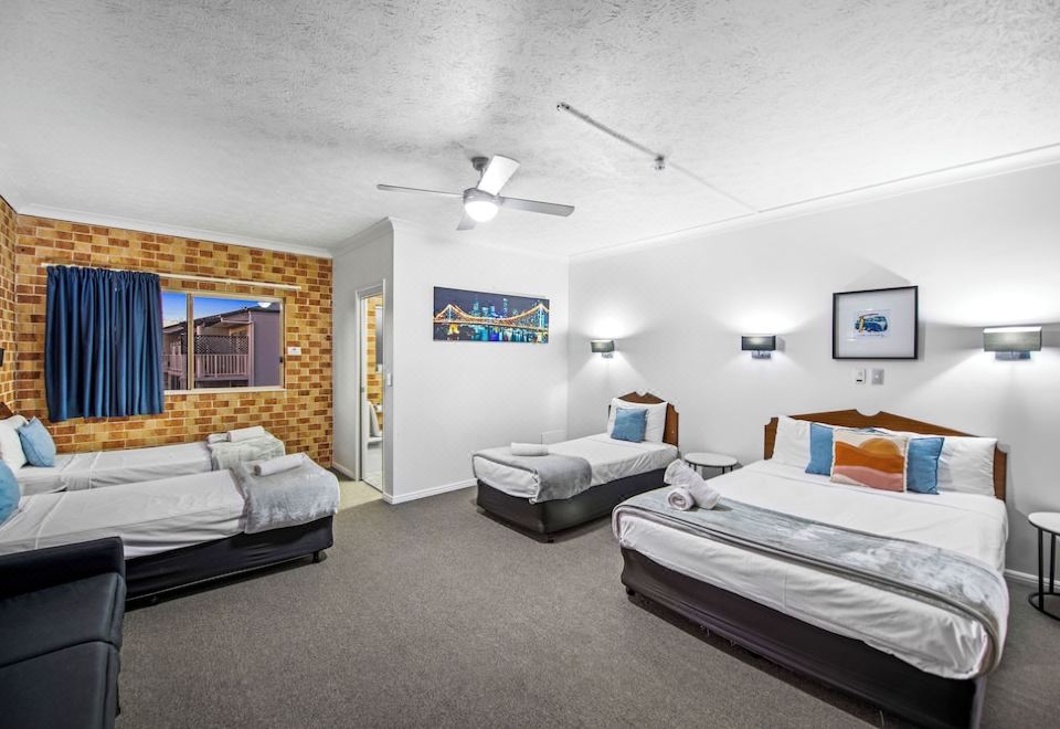 a hotel room with three beds , one on the left , one in the middle , and one on the right side of the room at Airport Clayfield Motel