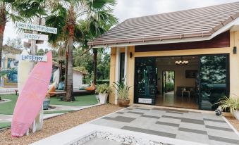 a modern , yellow - roofed building with a large glass door entrance and greenery surrounding it , including palm trees and other plants at Pimtara Beach Resort