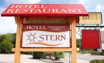 a sign for a hotel restaurant and cafe in a small town , with a red sign attached to the building at Stern