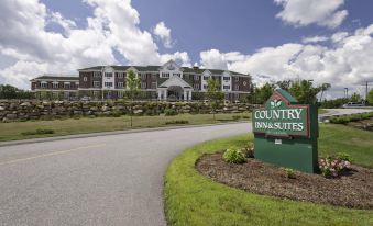 "a large building with a sign that reads "" country inn suites "" prominently displayed on the front of the building" at Country Inn & Suites by Radisson, Manchester Airport, NH