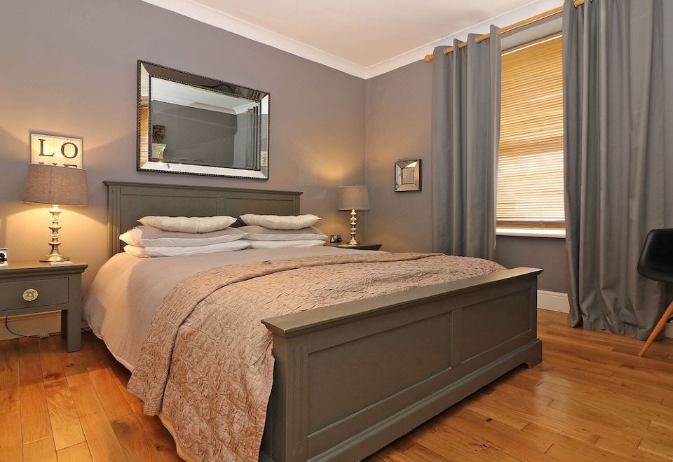a cozy bedroom with a large bed , wooden floors , and a mirror on the wall at Ocean View
