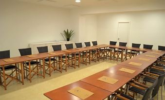 a large conference room with several rows of wooden tables and chairs arranged in a semicircle at Lago Resort Menorca Casas del Lago