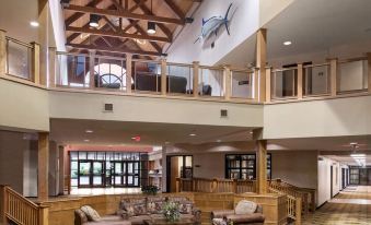 a spacious hotel lobby with high ceilings , wooden floors , and multiple couches and chairs arranged around the room at Arrowwood Resort at Cedar Shore