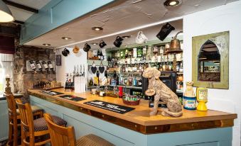 a bar with a wooden counter and stools , as well as various bottles and glasses on the counter at Old Posting House