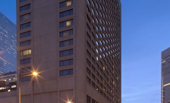 a tall building is lit up at night , with the surrounding cityscape and streetlights visible at Grand Hyatt Denver