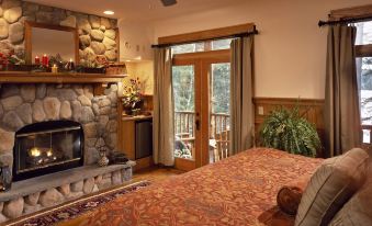 a cozy bedroom with a fireplace , a bed , and a door leading to a balcony at The Fern Lodge