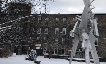 a snow - covered courtyard with a large metal sculpture in the middle , surrounded by snow - covered ground and trees at The Inn at Stone Mill