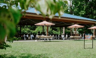 a group of people sitting at tables under umbrellas in a grassy area with trees in the background at Bicentennial Inn