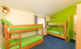 a room with four bunk beds arranged in a row , providing accommodation for multiple people at YHA Blaxhall - Hostel