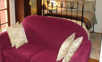 a purple couch with pillows in front of a bed , creating a cozy and inviting atmosphere at Albury Cottages