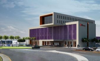 a modern building with a large purple facade and gray accents is surrounded by cars and people at Hilton Garden Inn Monterrey Airport