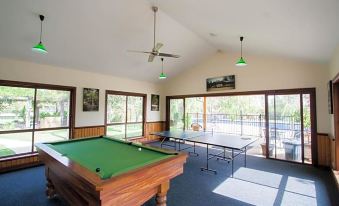 a large room with multiple tables , including a pool table , a ping pong table , and a dining table at Perricoota Vines Retreat