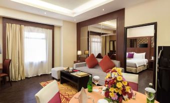 a modern hotel room with a living area , dining table , and large bed , all decorated in white and brown colors at Best Western Plus Makassar Beach