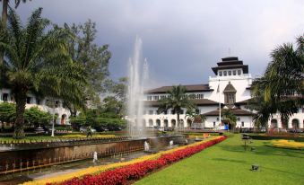 a large white building with a fountain in front of it , surrounded by colorful flowers at Super OYO Collection O Sweet Karina Bandung