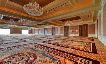 a large , ornate room with a gold and red patterned carpet and a chandelier hanging from the ceiling at Little America Hotel & Resort Cheyenne