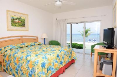 a bedroom with a large bed , floral bedspread , and a view of the ocean through sliding glass doors at Wyndham Reef Resort Grand Cayman