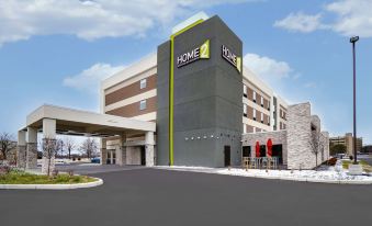 "a modern hotel with a gray and green color scheme , featuring a large sign that reads "" home 2 ""." at Home2 Suites by Hilton Springdale Cincinnati