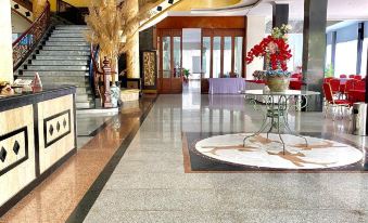 a large hotel lobby with a marble floor , a check - in desk , and multiple chairs arranged around it at Hotel Prima Indah