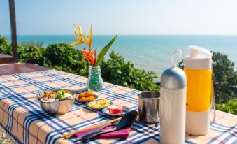 a table with a checkered tablecloth , various items such as bottles , food , and a vase of flowers , all set against the at Sea Horizon Resort