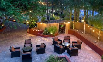 a well - lit outdoor area with a variety of seating options , including couches and chairs , under string lights at DoubleTree by Hilton Phoenix Tempe