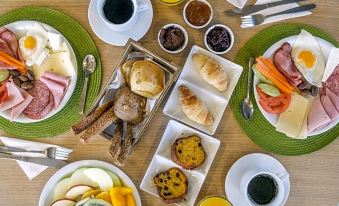 a table is set with a variety of food items including bread , fruit , and juices at Lotus Inn