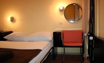 a bed with a red chair and a round mirror on the wall in a room at Zlatibor Hotel