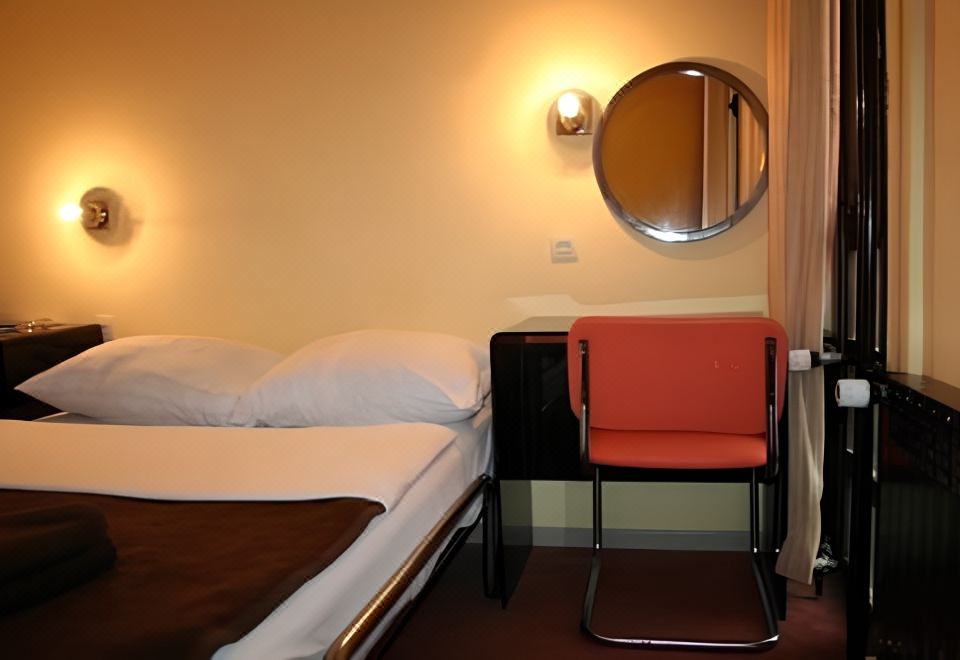 a bed with a red chair and a round mirror on the wall in a room at Zlatibor Hotel