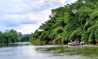 a group of people are on a boat in the water near a forested hill at Baan Rai Darun Home Stay and Scenery Raft