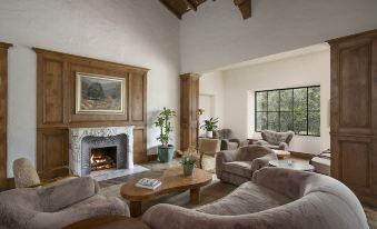 a cozy living room with wooden furniture , including a couch , chairs , and a fireplace , creating a warm and inviting atmosphere at The Inn at Rancho Santa Fe