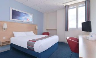 a hotel room with a large bed , red chairs , and a window overlooking the city at Travelodge Stonehouse