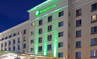 "a large hotel building with a green lit sign that reads "" holiday inn suites "" prominently displayed on the front" at Holiday Inn & Suites Hopkinsville - Convention Ctr
