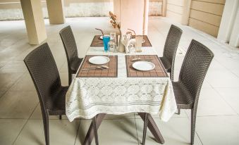 a dining table with two chairs and a white tablecloth , set for a meal in a room with beige walls at Hotel Nirvana