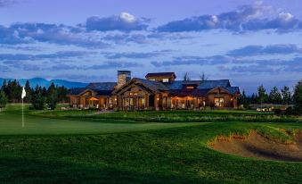 a large building with a green lawn in front of it , surrounded by trees and grass at Wilderness Club