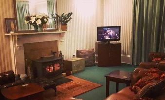 a cozy living room with a fireplace , a flat - screen tv , and a fireplace mantle at Rigg House B&B