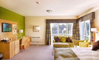 a hotel room with a large bed , a couch , and a window overlooking the city at Ramsey Park Hotel