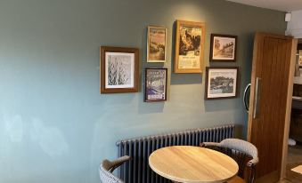 a small dining area with a wooden table , two chairs , and several framed pictures hanging on the wall at Old Swan