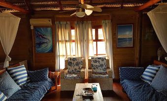 a cozy living room with wooden walls , large windows , and comfortable couches , under a ceiling fan at White Sands