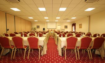 a large conference room with multiple rows of chairs arranged in a semicircle , facing a whiteboard on the wall at Hotel Corsica & Spa Serena