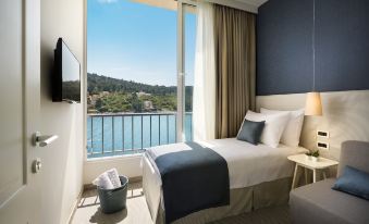 a hotel room with a large window offering a view of the water , a bed , and a tv at Aminess Lume Hotel