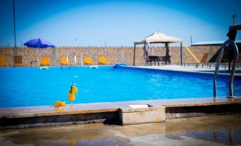 an outdoor swimming pool surrounded by a brick wall , with several lounge chairs placed around the pool area at Richmind Hotel