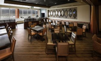 a large dining area with wooden tables and chairs , a bar , and a kitchen in the background at Cahuilla Casino Hotel