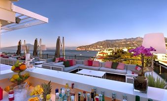 a rooftop bar with a view of the ocean , where people are enjoying drinks and food at Hotel Continental