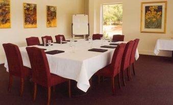 a conference room with a white table surrounded by red chairs and framed pictures on the wall at Cape Lodge