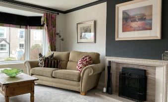 a cozy living room with a beige couch , a fireplace , and a painting on the wall at Ramsey House - Luxury Licensed B&B - Parking and Guest Lounge